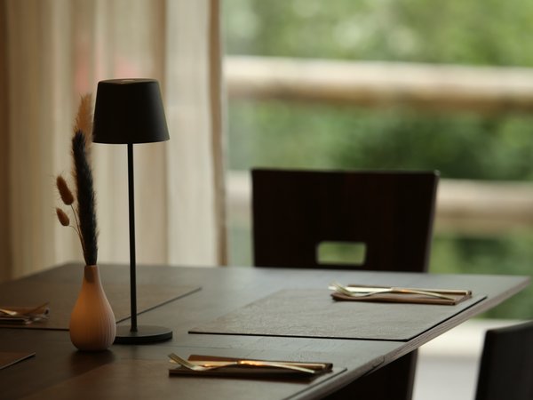 3 restaurants under one roof Elegant dining table with set places, lamp, and vase by window