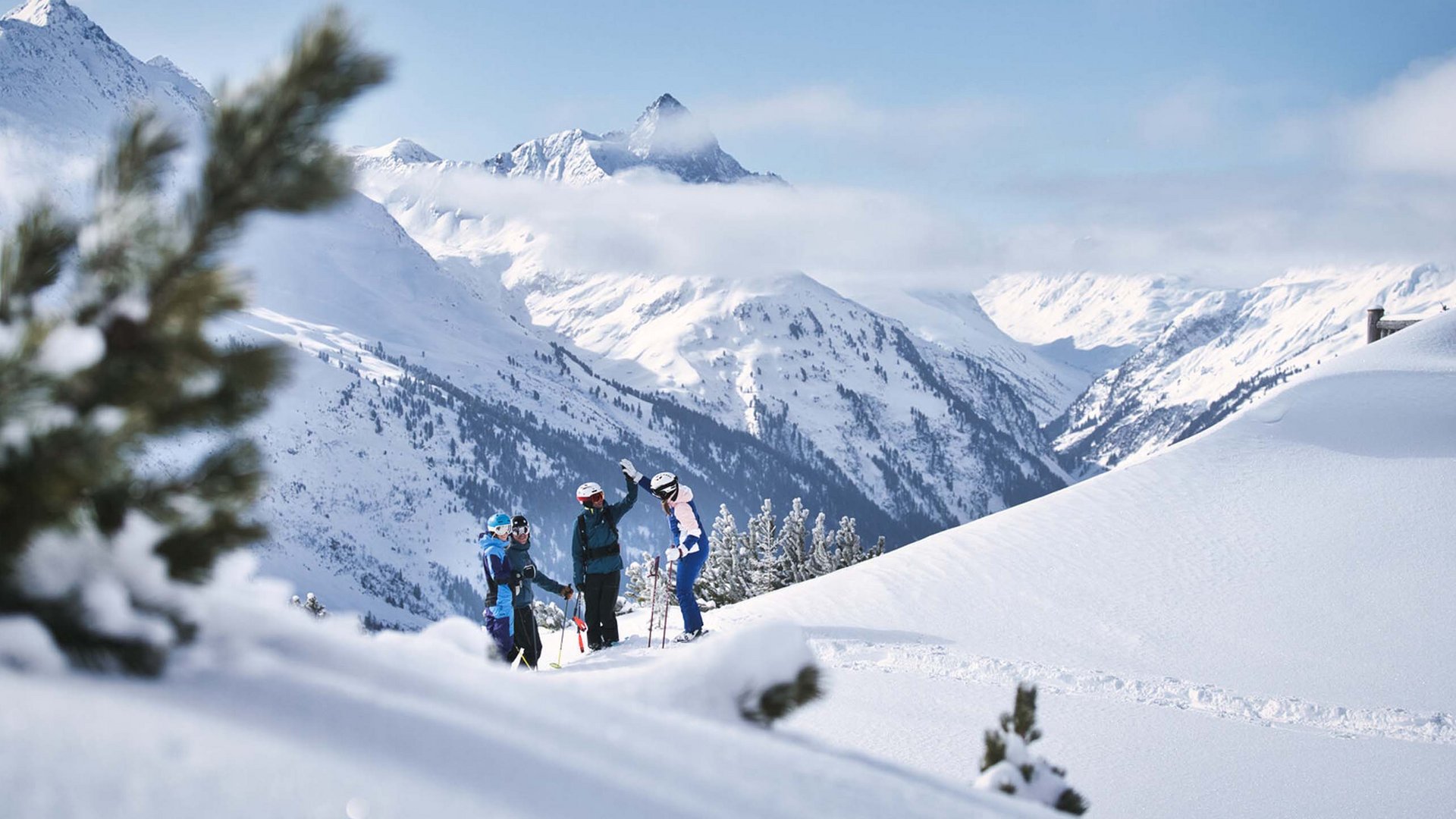 Skiers celebrating in front of snowy mountains under clear sky