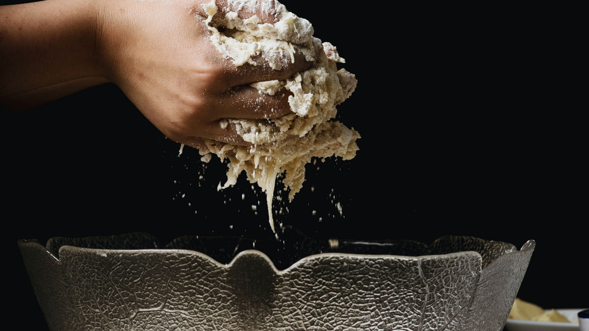 Hand knetet Teig über einer Glasrührschüssel auf Holztisch