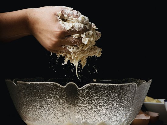 St. Anton: summer holidays, winter fun Hand kneading dough over a glass mixing bowl on wooden table