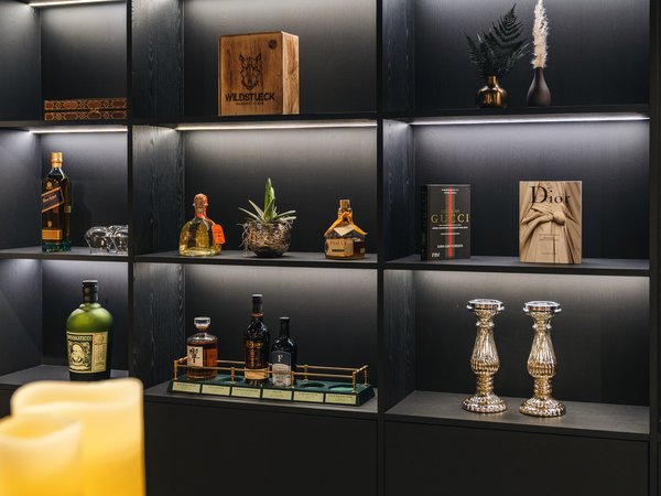 Lit shelf with liquor bottles, books, and decorative items