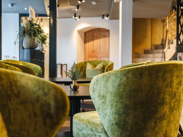 Cozy seating area with green velvet chairs and small decorative vase on table