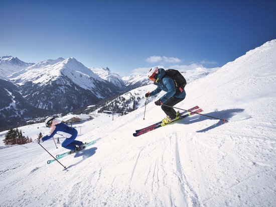St. Anton: Sommerurlaub, Winterspaß Zwei Skifahrer fahren einen schneebedeckten Hang in den Bergen hinab
