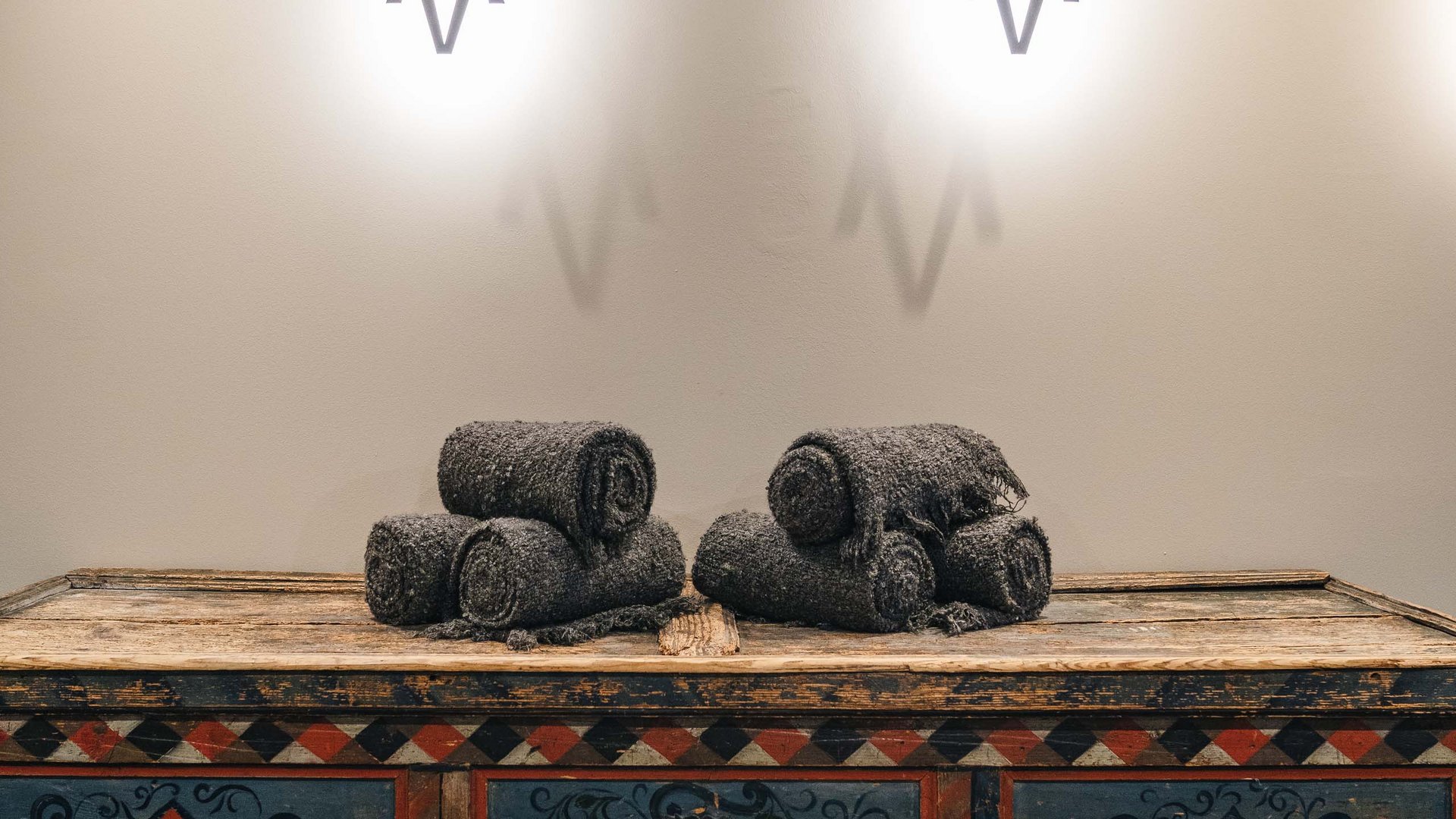 Antique painted chest with gray rolled towels and wall sconces