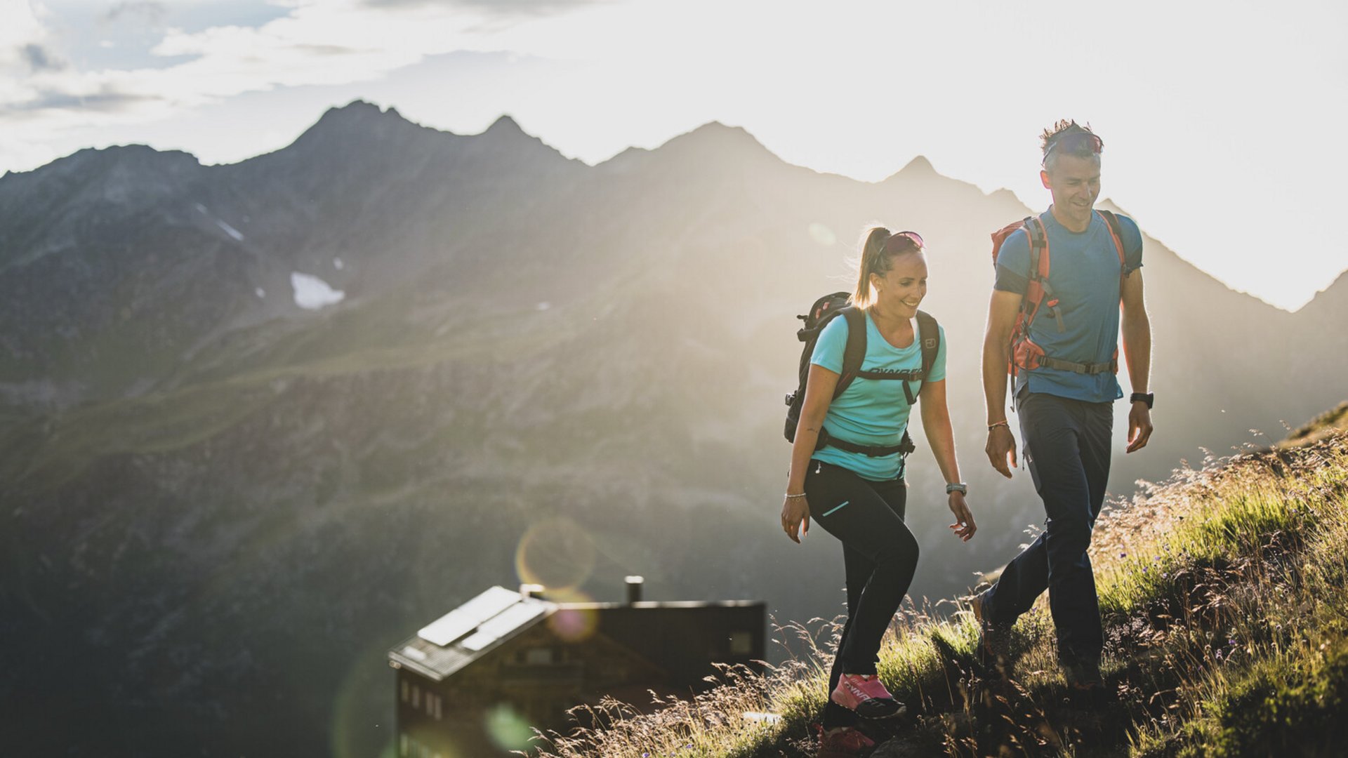 Couple hiking in the mountains at sunset with backpacks