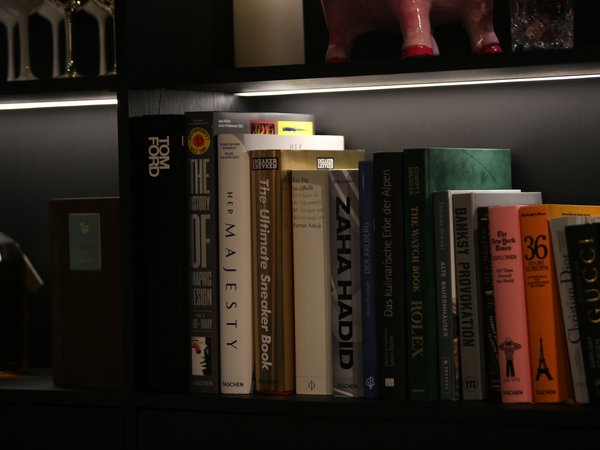 Books and bottle on a black shelf with lighting